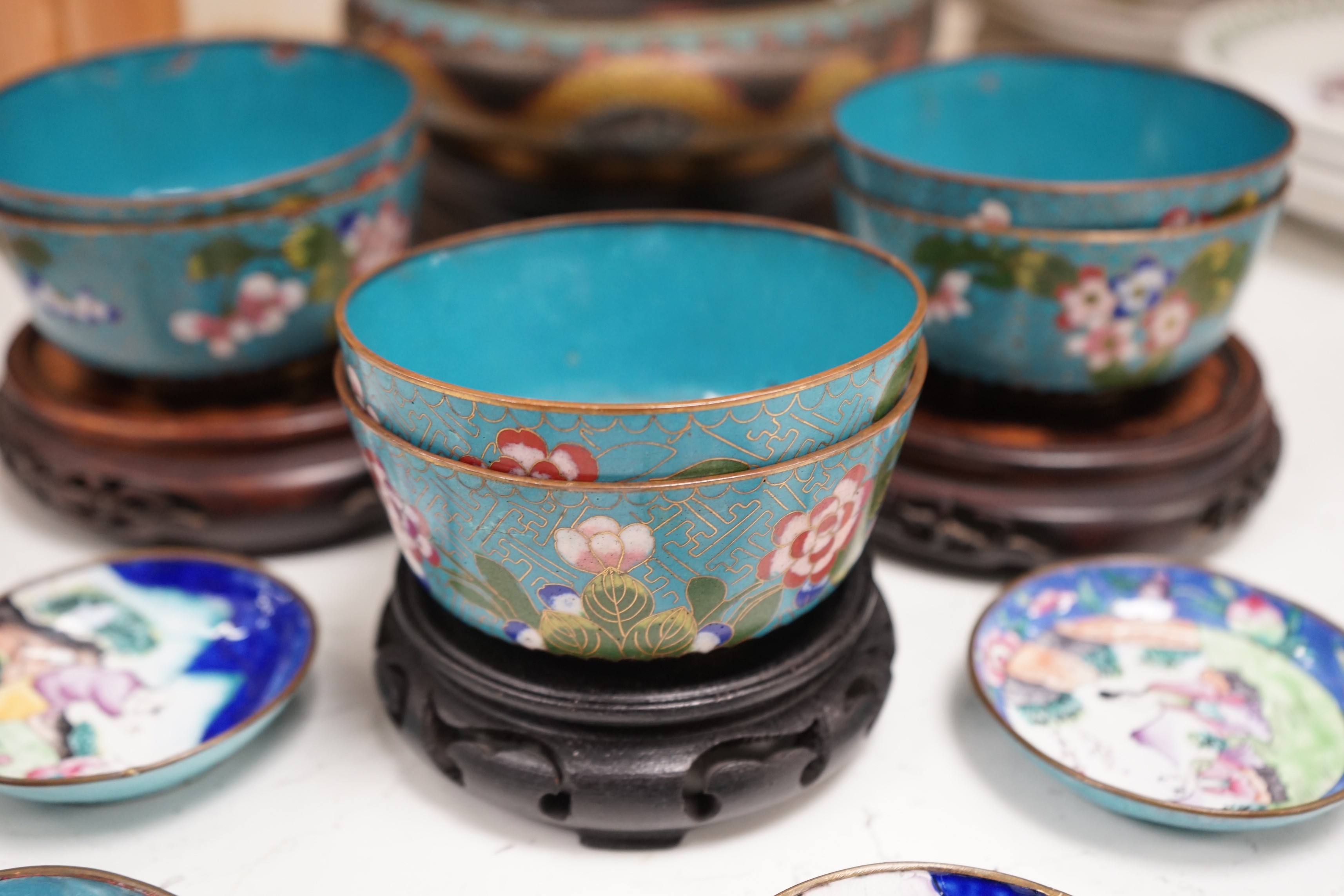 A Chinese cloisonné enamel 'dragon' bowl, six Chinese floral cloisonné enamel bowls and four Canton enamel dishes and wood stands